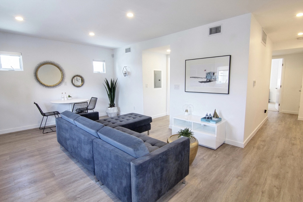 a living room with a gray couch and a kitchen in the background
